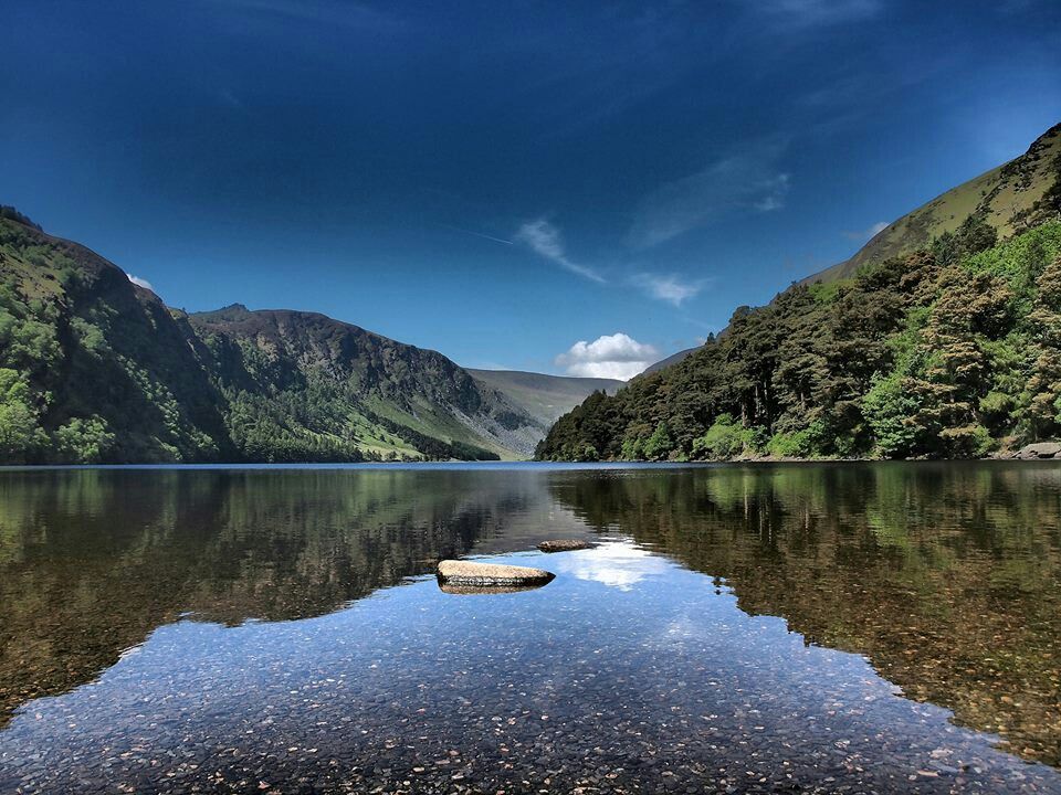 Serene landscape of Upper Lake in Glendalough, County Wicklow, Ireland, surrounded by lush greenery and mountains