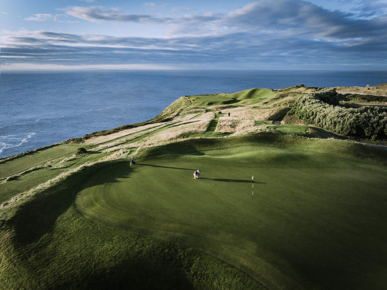 A scenic photo of the 2nd hole, known as the 'Gun Hole', at Old Head Golf Links in Kinsale, County Cork, Ireland, showcasing the lush green course and stunning ocean views. 