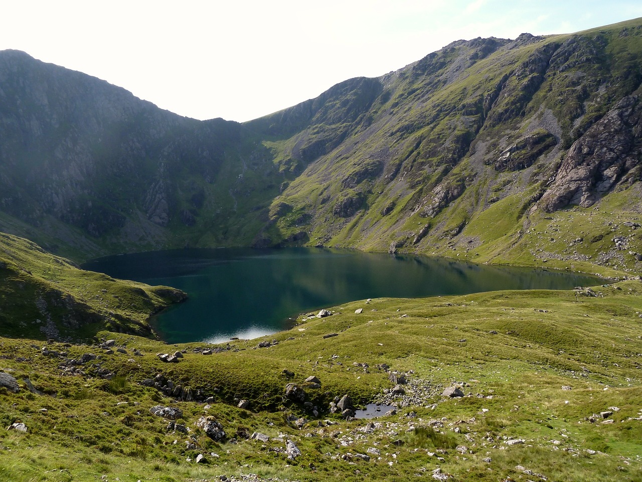 A majestic photo of Cadair Idris, a iconic mountain in Snowdonia National Park, Wales, UK, showcasing its rugged, snow-capped peak rising dramatically above a serene lake, surrounded by lush green valleys and scenic hiking trails.