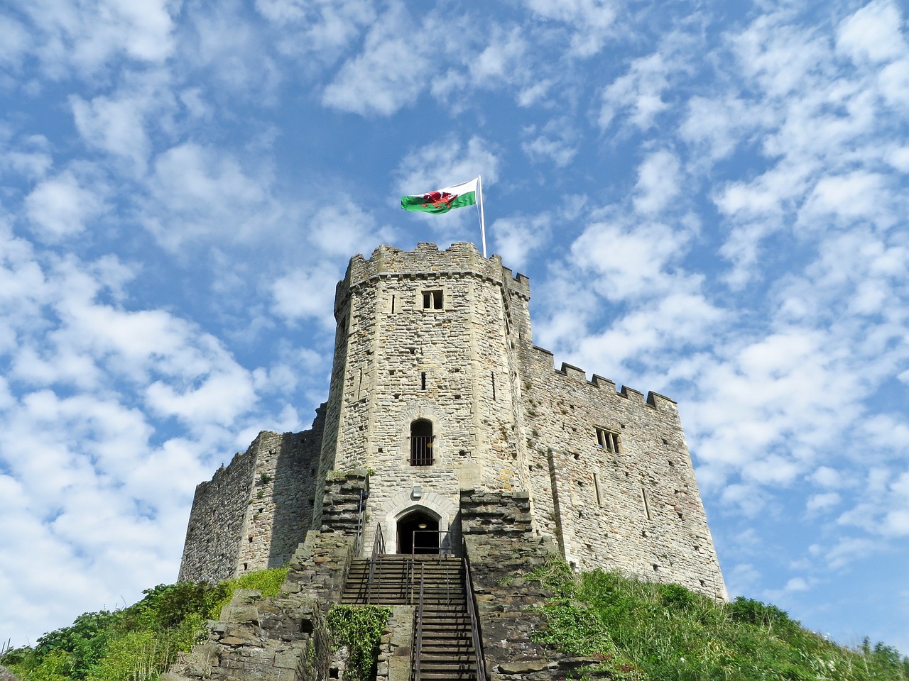 A stunning photo of Cardiff Castle, a medieval fortress situated in the heart of Cardiff, Wales, showcasing its impressive stone walls, towers, and battlements, surrounded by lush green gardens and a moat.