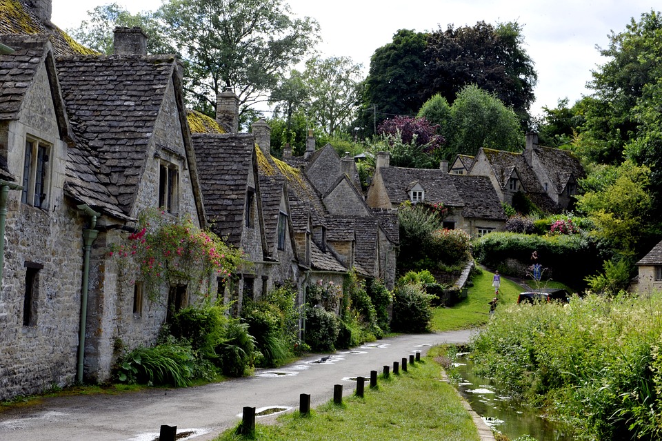 A scenic snapshot of a Cotswold village tour, capturing the area's classic architectural charm, rolling hills, and vibrant village life.