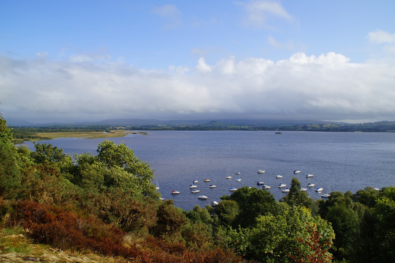 Scenic Loch Lomond, Scotland's largest freshwater lake, surrounded by rolling hills and majestic mountains, reflecting a serene atmosphere and breathtaking natural beauty. 