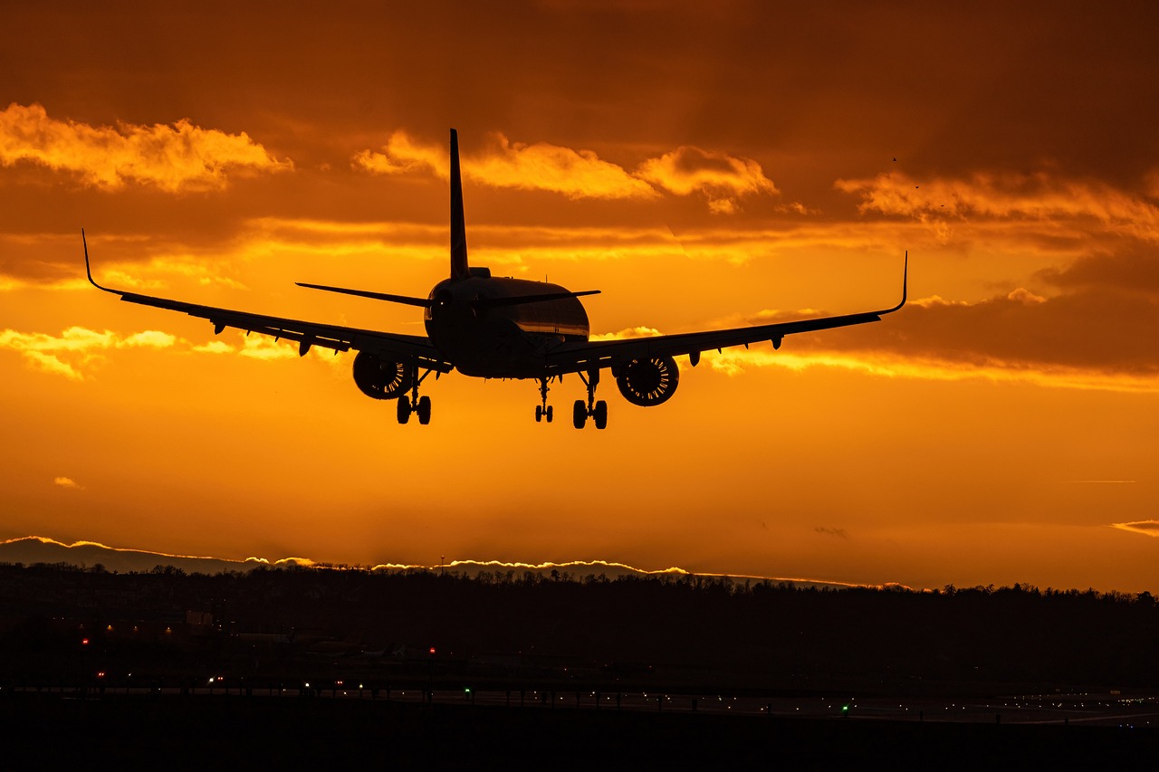 A commercial airdplane soars through the sky at sunset 