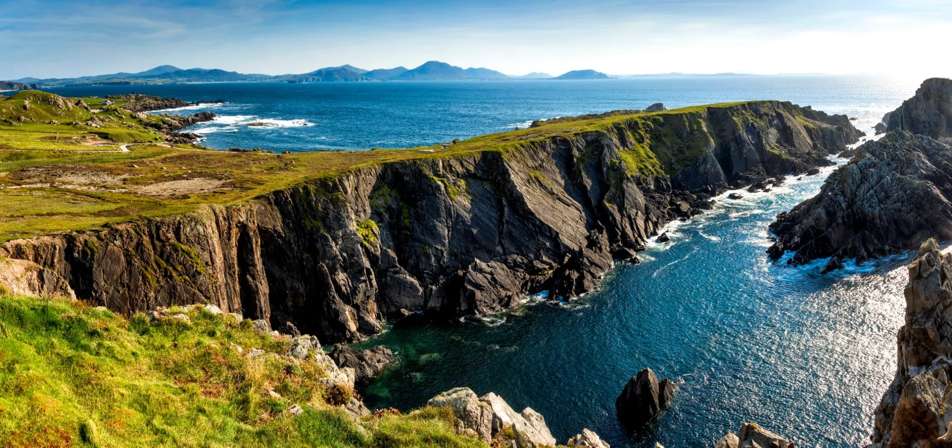 Dramatic coastal cliffs in Donegal, Ireland overlooking the Atlantic Ocean with rugged rock formations and green hills