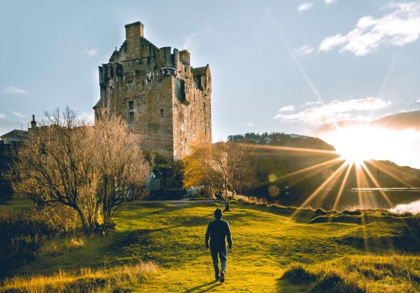 Man walking towards Eilean Donan Castle, Highlands, Scotland.